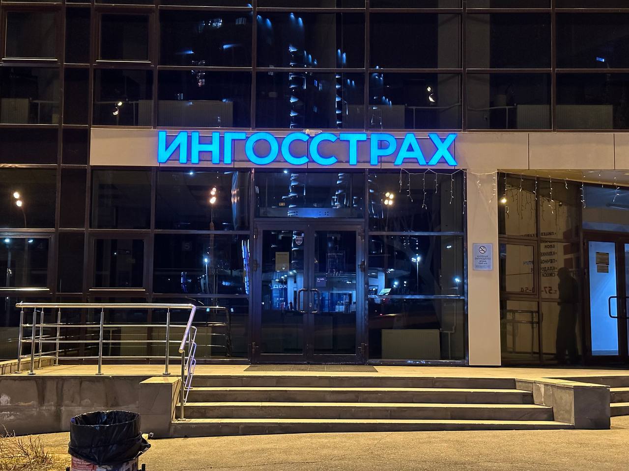 Световая вывеска «Ингосстрах» с голубой подсветкой на фасаде вечером