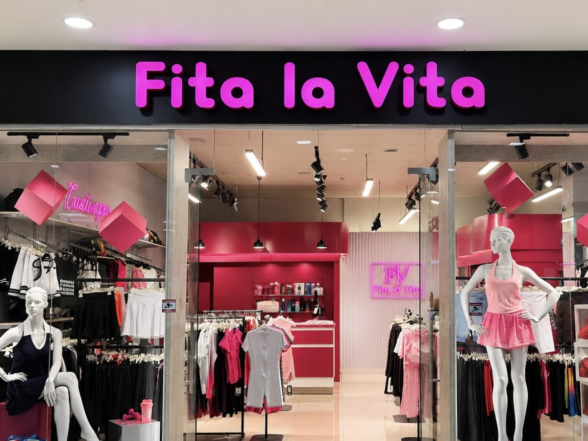 Розовая светящаяся вывеска «Fita la Vita» в торговом зале магазина одежды