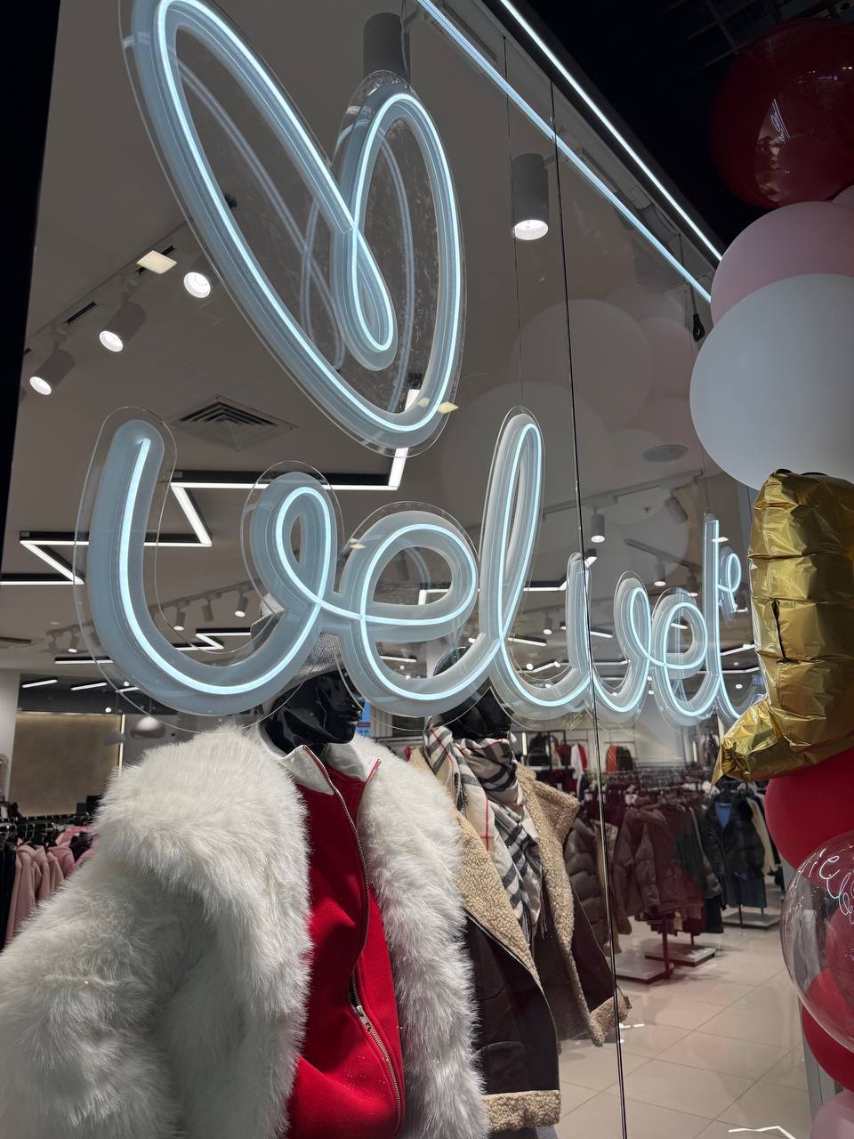 Голубая неоновая вывеска «velvet» на витрине магазина одежды